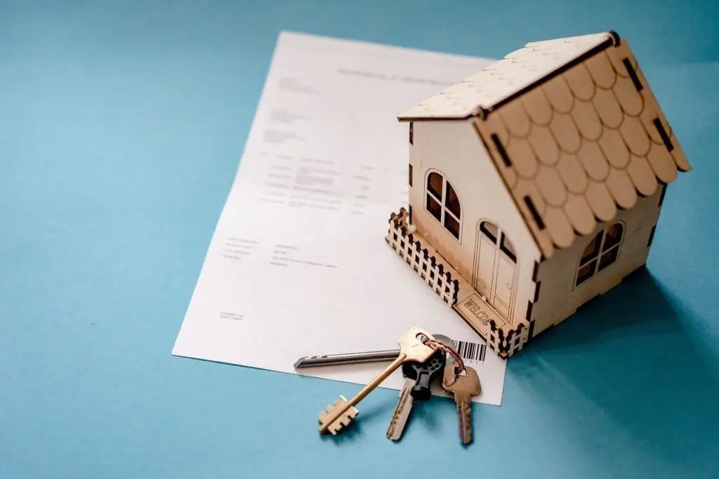 Picture of a wooden home with paper and keys next to it.